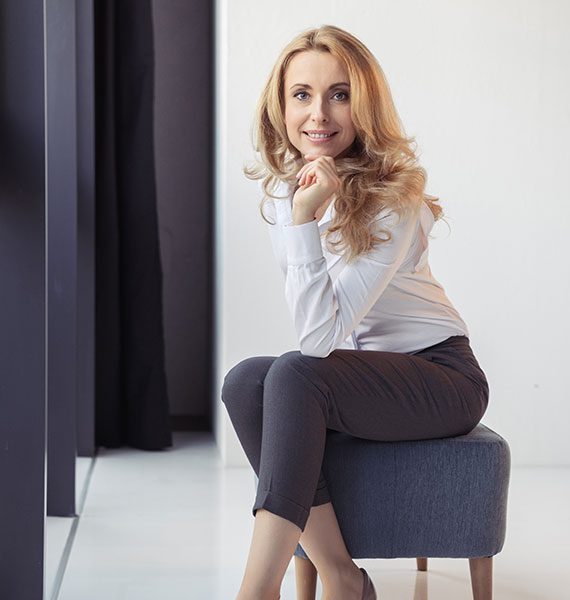 Smiling woman sitting on a stool by the window. Smiling woman sitting on a stool by the window.
