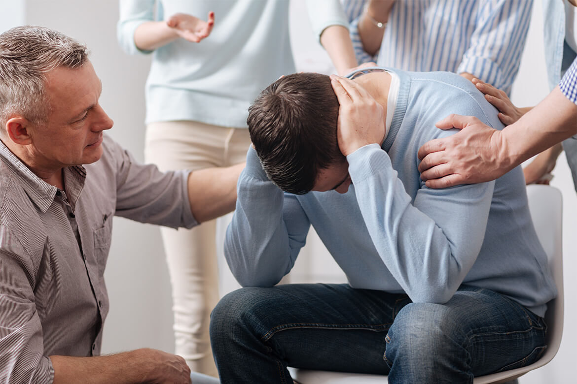 A man is comforted by friends during a difficult moment.
