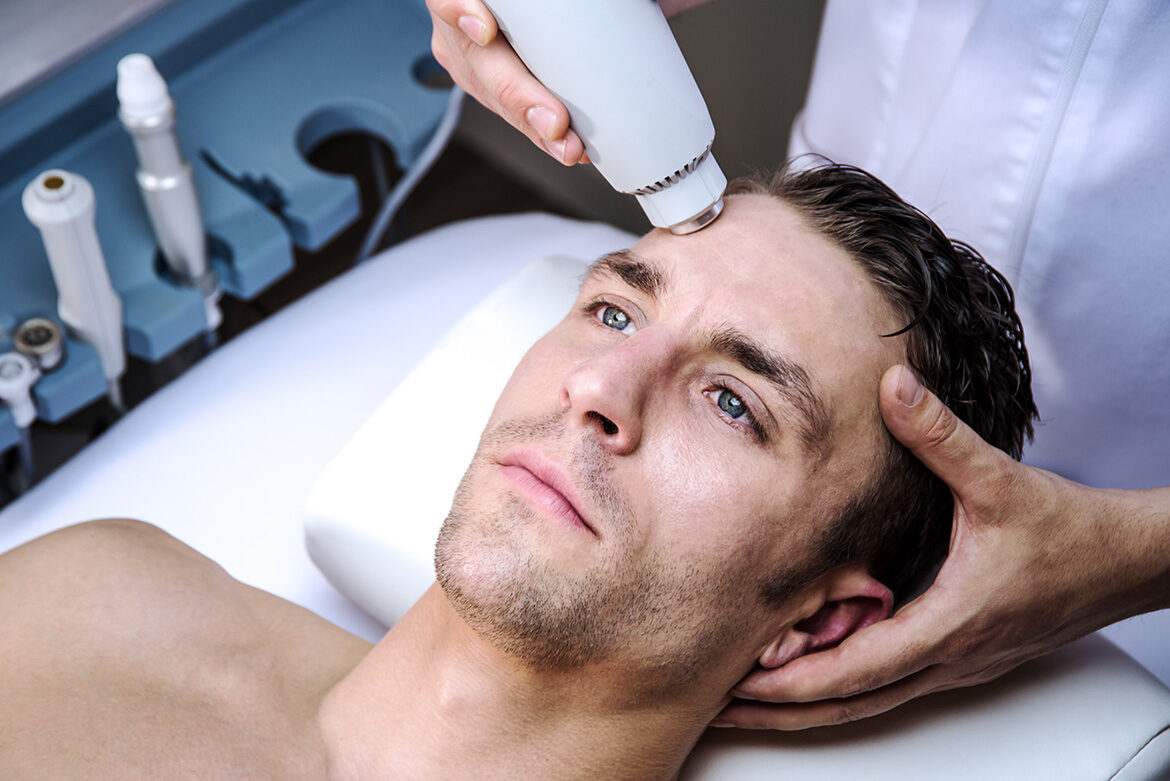 Man receiving a facial treatment with a handheld device at a spa.